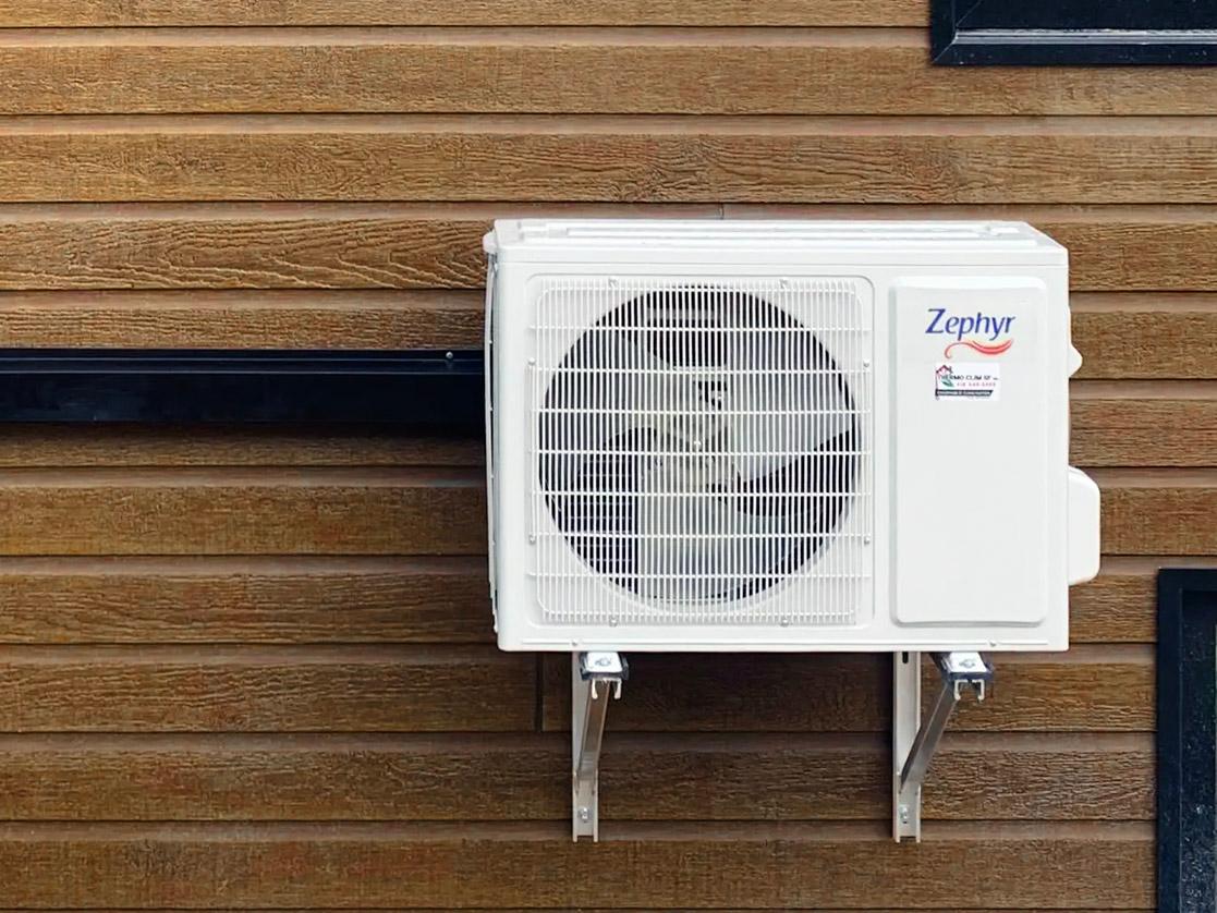 Unité extérieure de climatisation Zephyr installée sur un mur en revêtement bois.