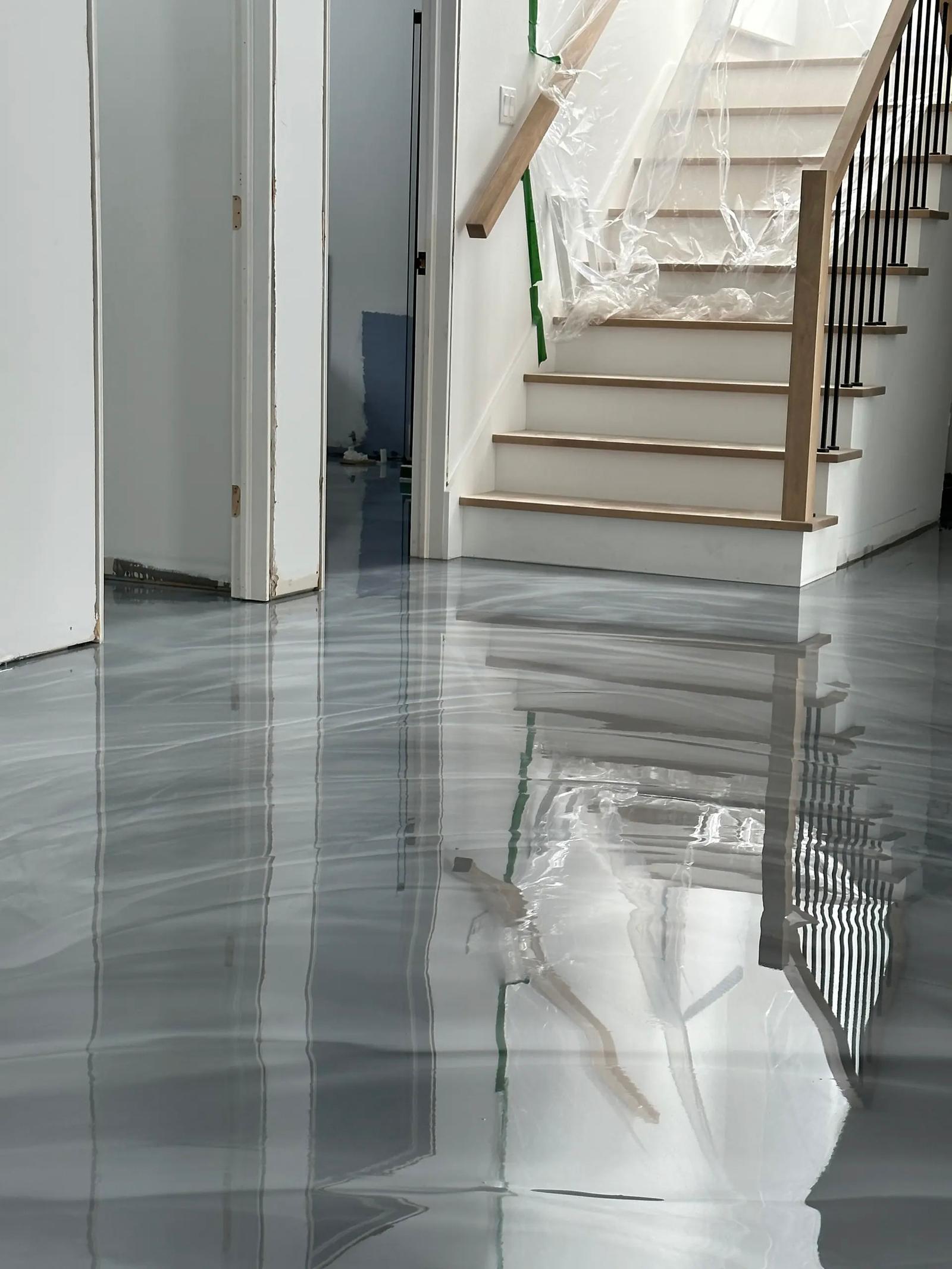 Plancher en résine époxy fraîchement coulé avec effet marbré gris et finition ultra-brillante dans une maison en rénovation.