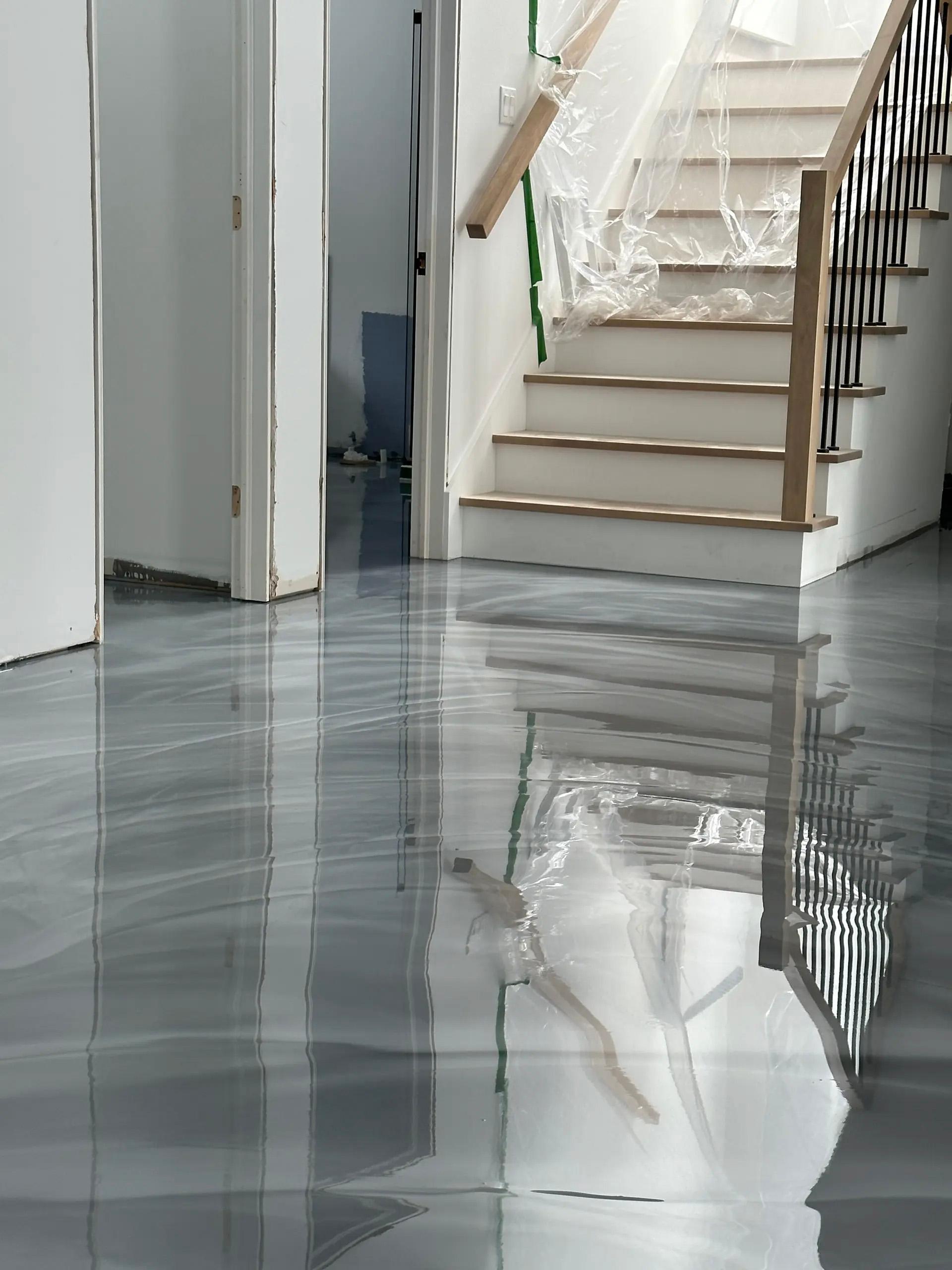 Plancher en résine époxy fraîchement coulé avec effet marbré gris et finition ultra-brillante dans une maison en rénovation.