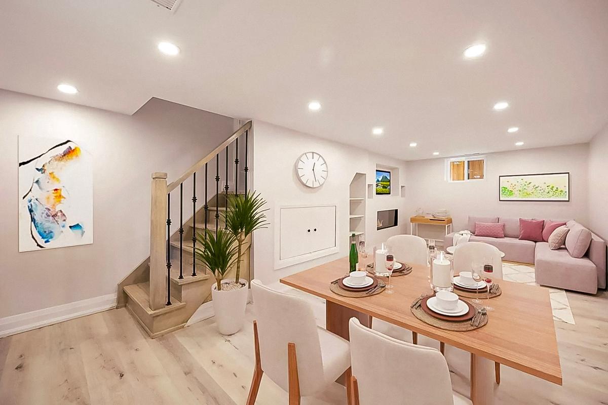 Sous-sol aménagé avec salle à manger et salon, décoré dans un style moderne avec un escalier en bois, des murs blancs et un éclairage encastré.