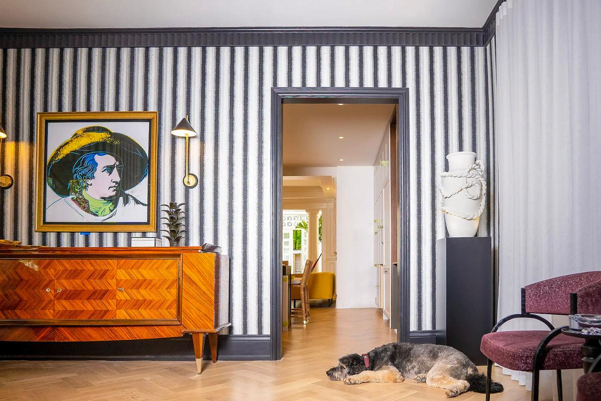 Intérieur raffiné avec papier peint rayé, meuble design en bois, et parquet en chevron.