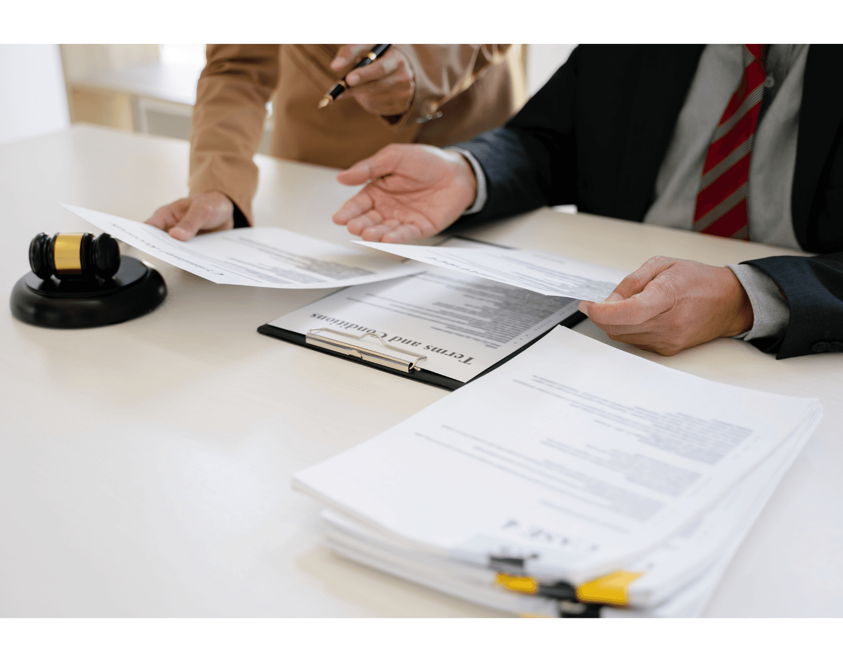 Réunion juridique avec des documents contractuels et un marteau de juge sur une table.