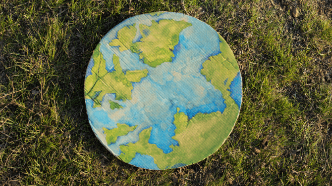 Tableau de peinture en forme de planête terre posée sur l'herbe