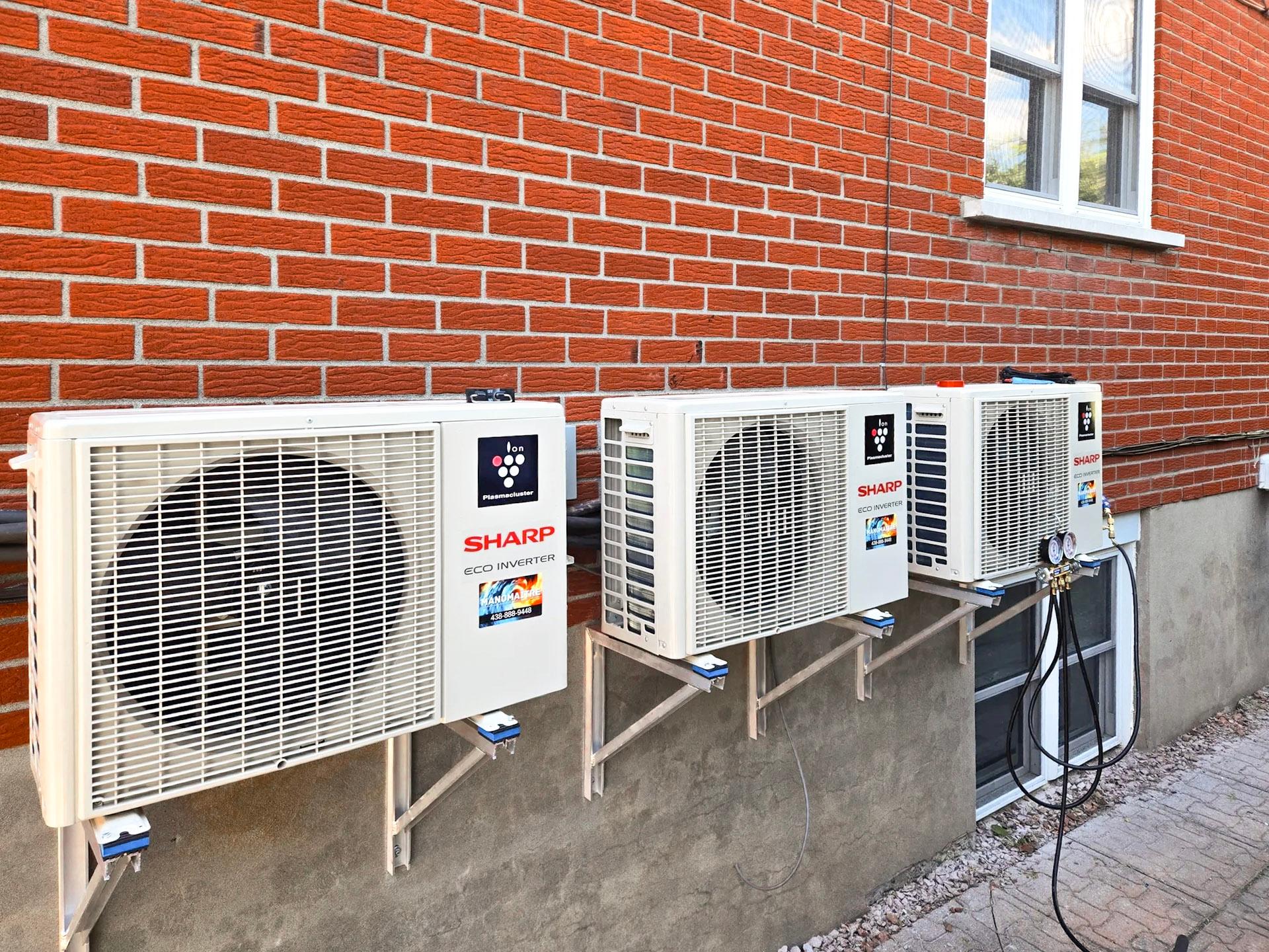 Installation de trois unités extérieures de climatiseur mural Sharp sur un mur en briques rouges. Solution de climatisation performante pour les grandes maisons.