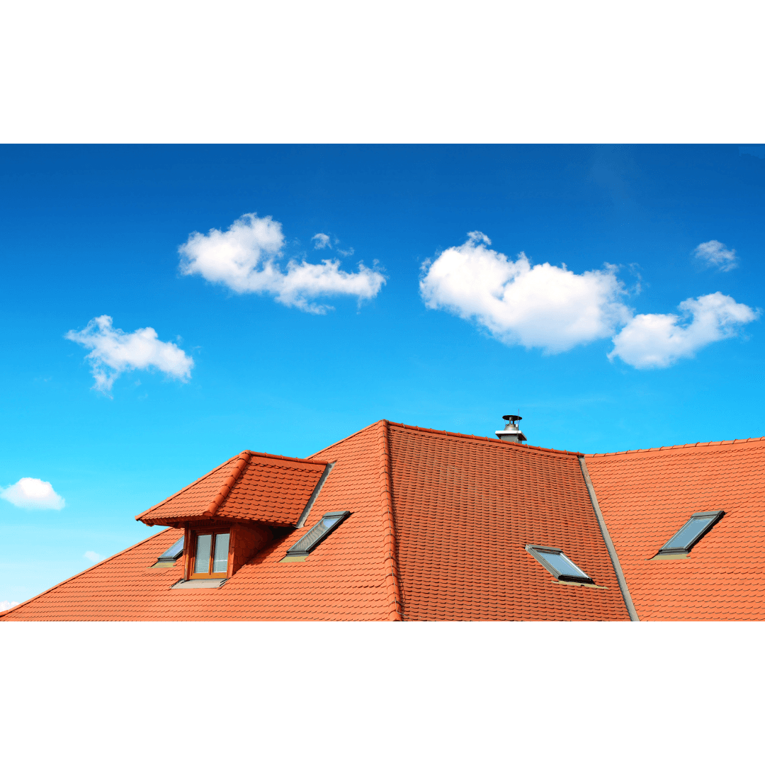 Toit en tuiles de terre cuite avec fenêtres modernes et lucarne, sous un ciel bleu parsemé de nuages.