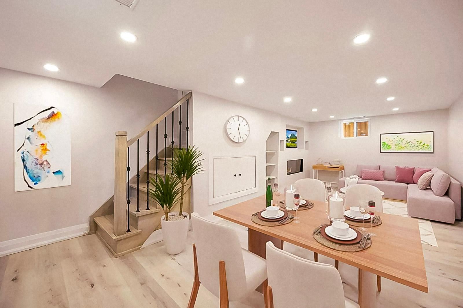 Sous-sol aménagé avec salle à manger et salon, décoré dans un style moderne avec un escalier en bois, des murs blancs et un éclairage encastré.