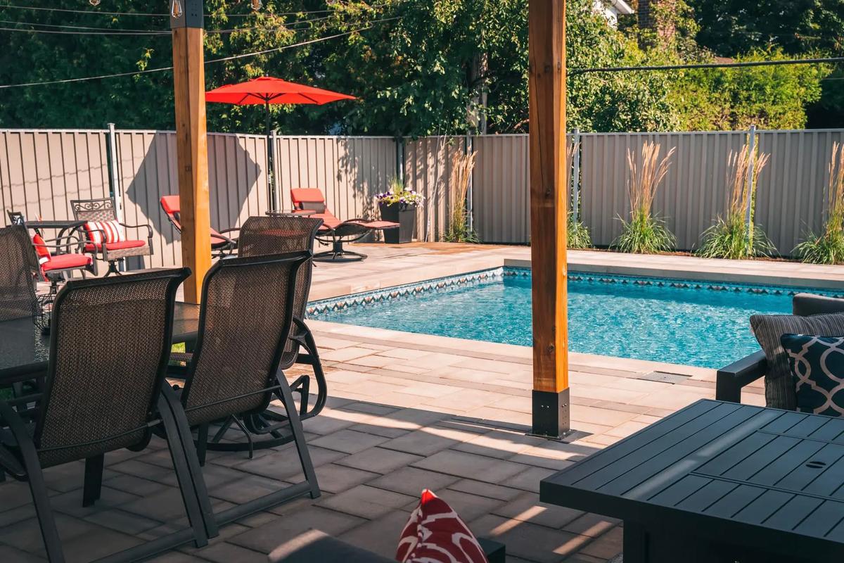 Patio moderne avec mobilier extérieur, piscine creusée et aménagement paysager clôturé